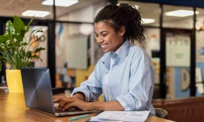 side-view-smiley-woman-working-with-laptop-office-scaled.jpg