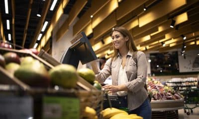 Woman at supermarket using self service digital scale to measure the weight of fruit.